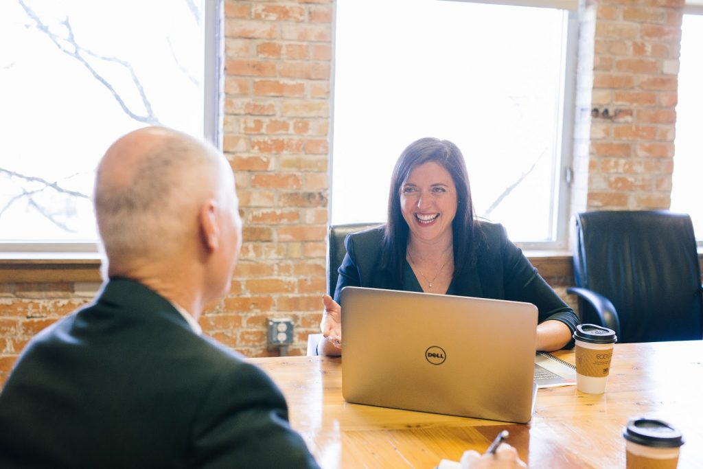 a man and a woman sitting at a table with a laptop