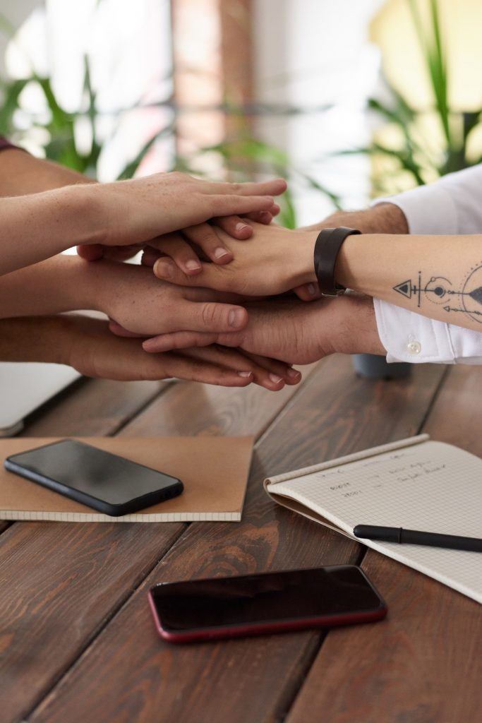 a person's hands on a table with a pen and a phone