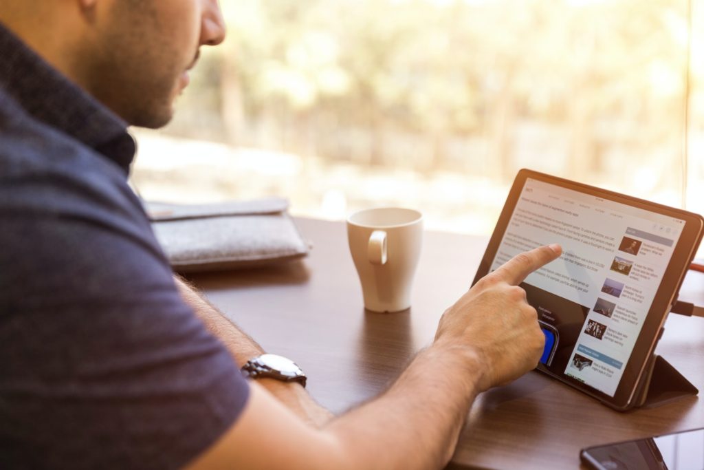 a man sitting at a table with a tablet and a cup of coffee