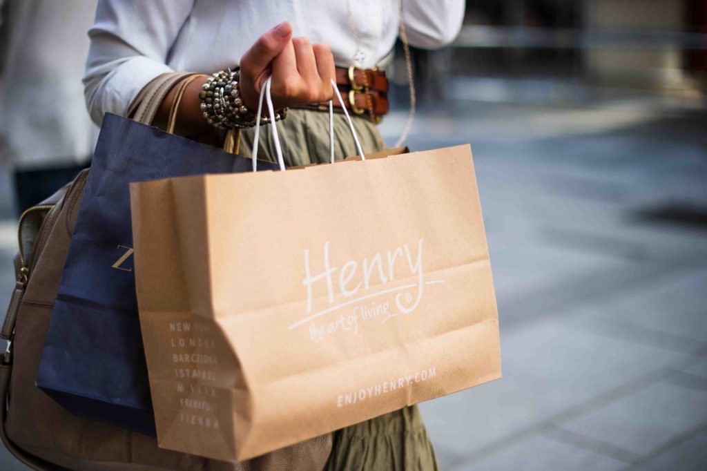 a person holding a brown bag with a white notepad and a brown bag with a white string