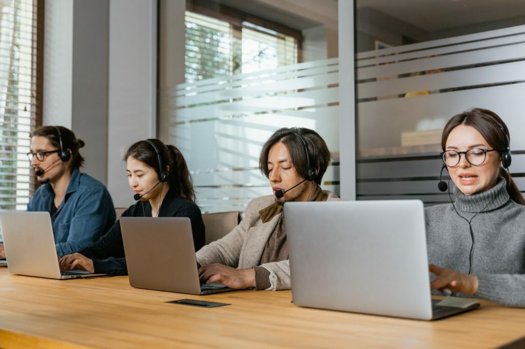 a group of people sitting at a table with laptops