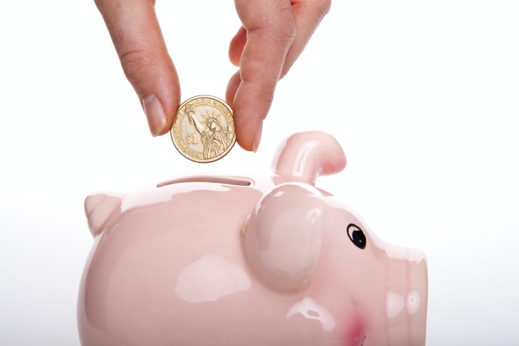 a hand holding a small piggy bank