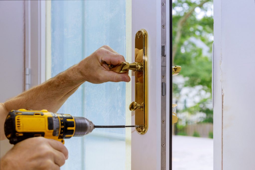 Closeup of a professional locksmith installing or new lock on a house door with screwdriver