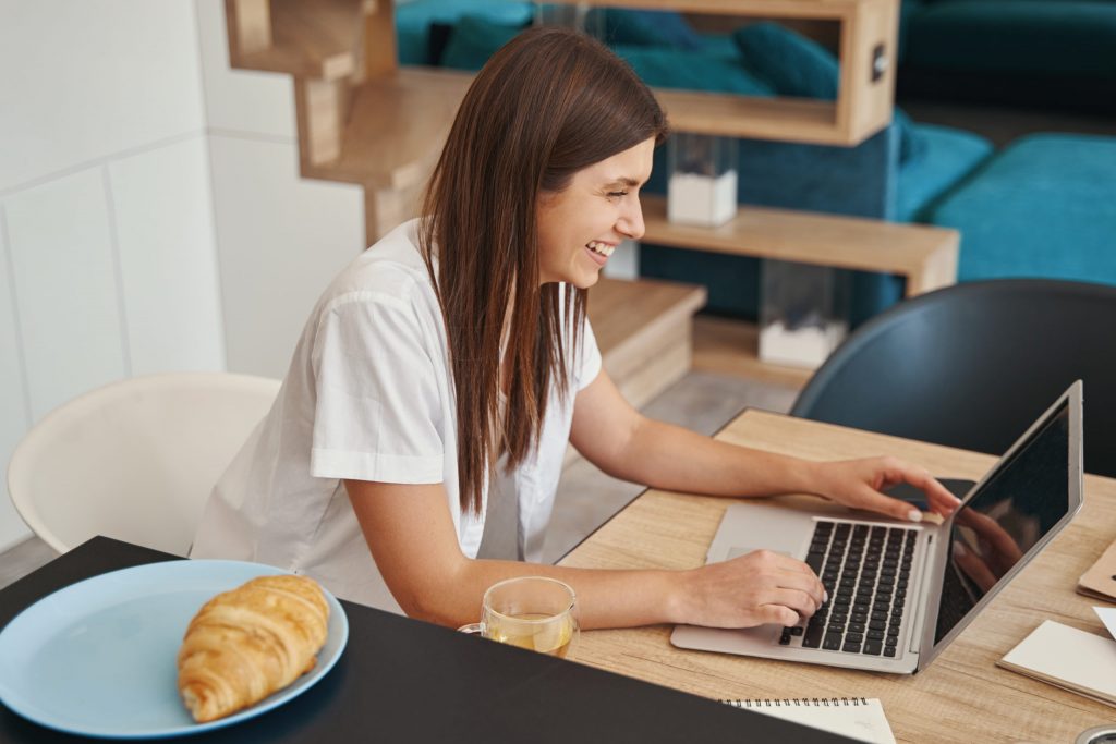 Joyful remote worker sitting at her laptop