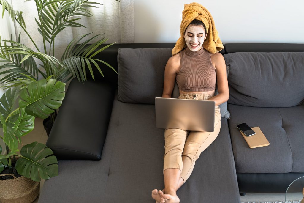 Young woman using laptop while having skin care day at home