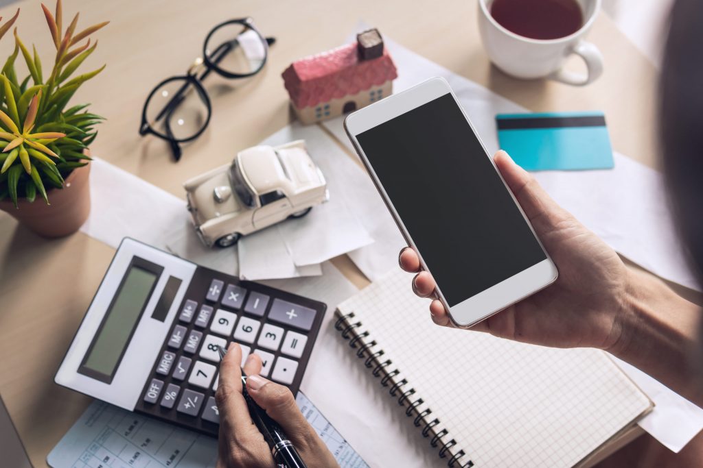 Young woman using smart phone and checking bills