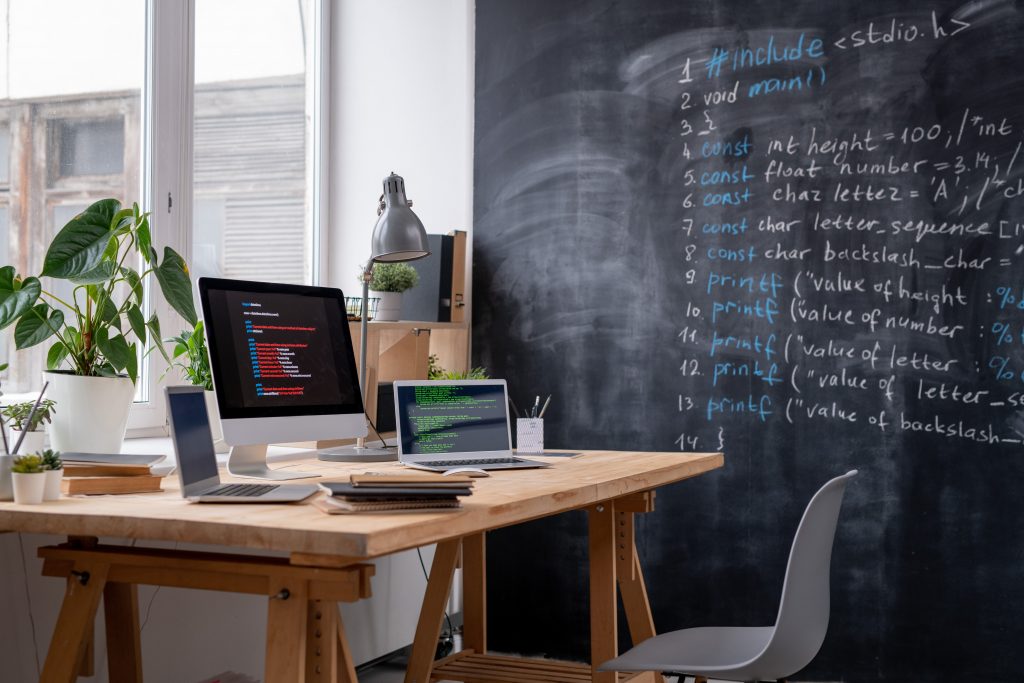 Workplace of it engineer by office window and blackboard with formula