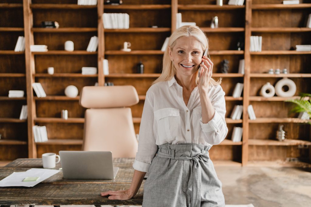 Boss talking on smartphone, calling her friends, colleagues, business partners working in office