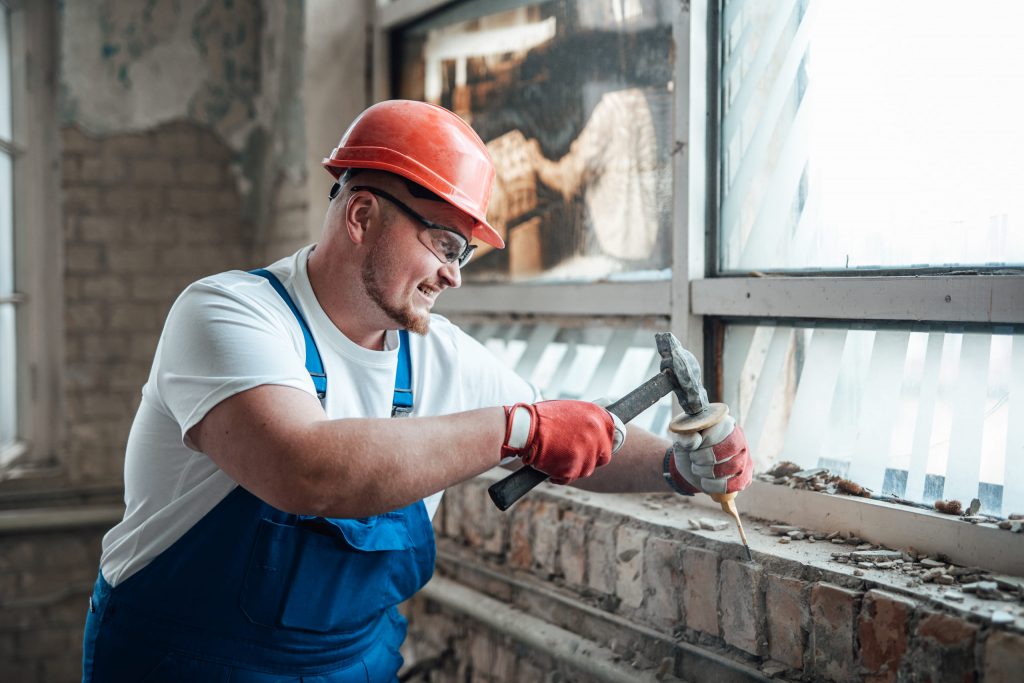 contractor wielding a hammer to destroy old brick       utc scaled