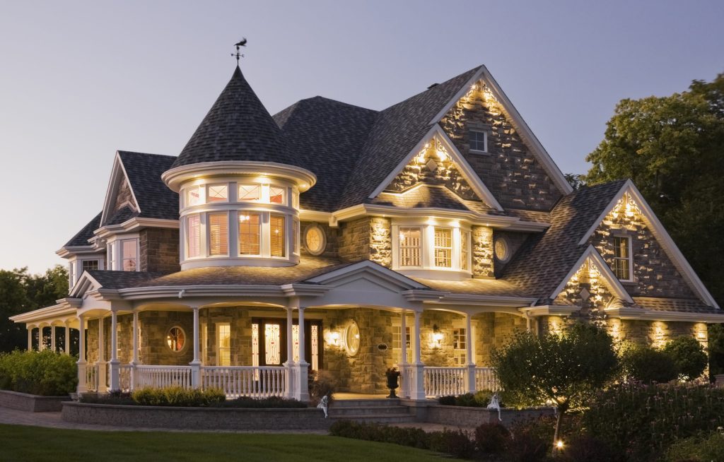 Elegant grey stone house with white trim and blue roof at dusk in summer, Quebec, Canada