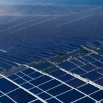 a wide array of solar panels stretches out under the clear blue sky on a sunny day.
